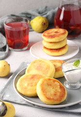 Traditional Ukrainian dish syrniki with berry jam and sour cream on grey plate on light background, Closeup