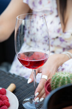 A glass of red wine that a girl keeps at a party at a restaurant. Vertical image.