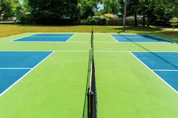 Recreational sport of pickleball court in Michigan, USA looking at an empty blue and green new court at a outdoor park. Middle Court View.