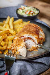 Fried chicken breast stuffed with bacon and cheese served with chips and salad.