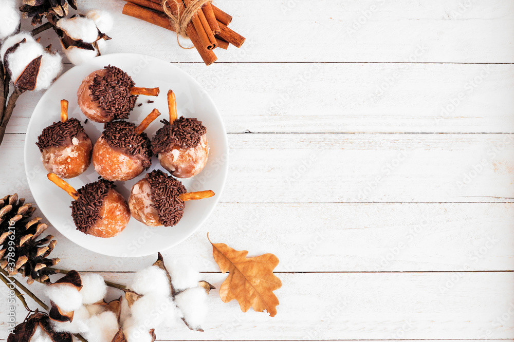 Poster autumn acorn shaped donut holes. top view side border on a white wood background with copy space.