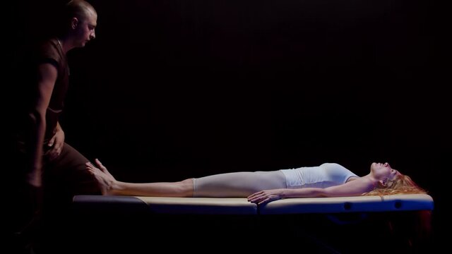 Session with a chiropractor - young woman lying on her back and the therapist abruptly pulls out her leg