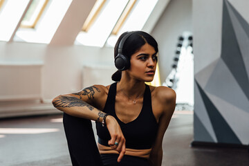 Woman in sportswear taking break and listening to music in gym