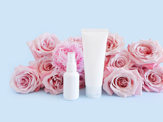 Mockups of two unbranded white bottle for branding and label and light pink roses on a pastel blue background. One of them is squeeze bottle plastic tube. Other is plastic spray bottle.