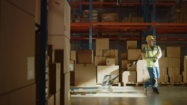 Worker Moves Cardboard Boxes using Hand Pallet Truck, Walking between Rows of Shelves with Goods in Retail Warehouse. People Work in Product Distribution Logistics Center. Side View Slow Motion