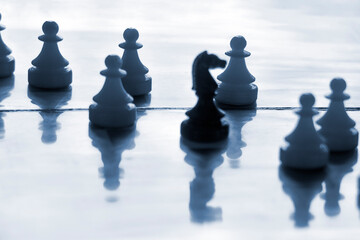 Pieces from plastic travel chess set, white pawns and black knight, on soft chessboard. Selective...