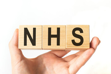 Hand holds wooden cubes with letters nhs. Medicine concept image.