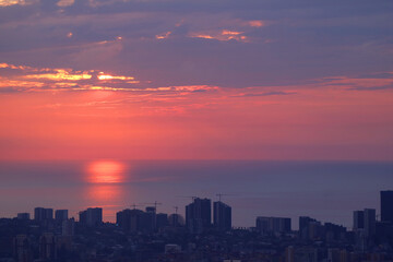 Reflections of the sunlight over the sea with group of skyscrapers and construction area in foreground