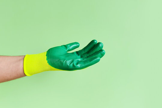 Male hand in a glove for working in the garden, vegetable garden. Worker showing outstretched palm gesture. Place for your product, Copy space.