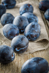 Still life with plums on wooden background. Vertical image.