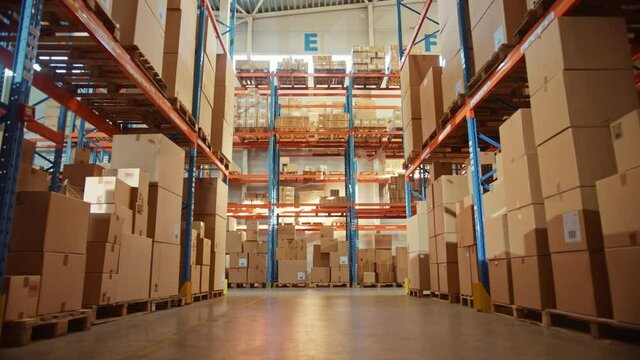 Big Retail Warehouse full of Shelves with Goods in Cardboard Boxes and Packages. Logistics, Sorting and Distribution Facility for Product Delivery. Low Moving Backward Between Rows of Shelves Camera