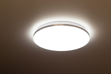 round flat lamp shines on the ceiling in the dark