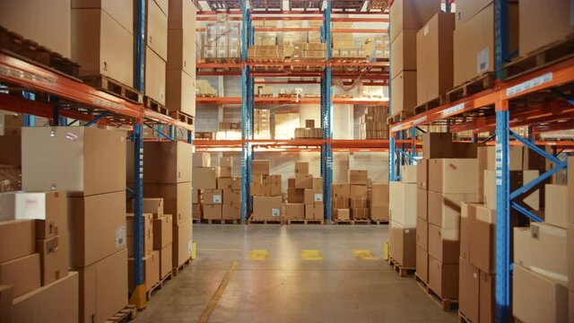 Big Retail Warehouse full of Shelves with Goods in Cardboard Boxes and Packages. Logistics, Sorting and Distribution Facility for Product Delivery. High Moving Backward Between Rows of Shelves Camera
