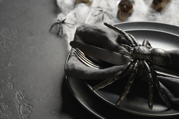 Halloween black table setting with spider, skull and web on black dark table. Close up. Copy space.