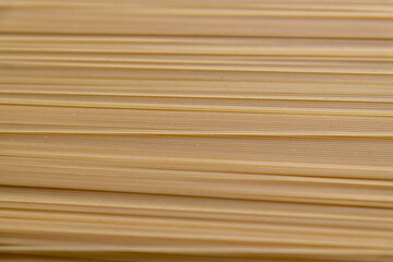 Abstract food background of raw uncooked spaghetti pasta made from milled durum wheat. Selective...