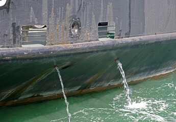 Water flows from the tube on the hull of ship