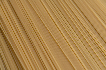 Abstract food background of raw uncooked spaghetti pasta made from milled durum wheat. Selective focus. Copy space for your text. Italian cuisine theme.
