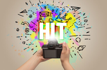 Close-up of a hand holding digital camera with abstract drawing and HIT inscription