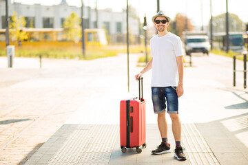 Fototapeta na wymiar Travelling guy with suitcase wearing smart style clothes waiting for transport.