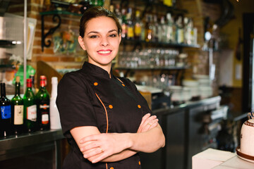 Pretty waitress posing in restaurant bar looking at camera