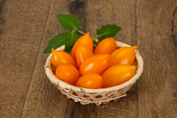 Yellow tomato heap in the wooden bowl