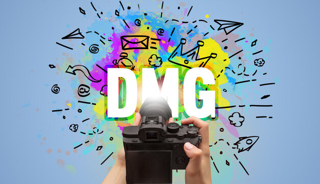 Close-up of a hand holding digital camera with abstract drawing and DMG inscription