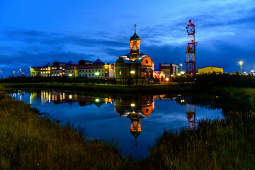 Russian orthodox church in Yamburg - small town in north of Russia at night time with reflection in water.