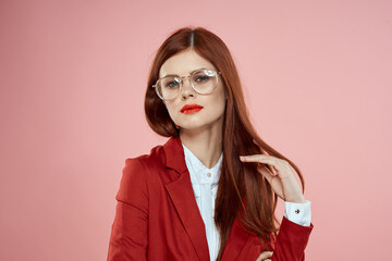 woman in red jacket with glasses red lips long hair pink background