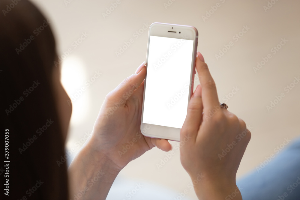 Wall mural close up of young woman using smartphone with empty white mock up screen left for copy space. client