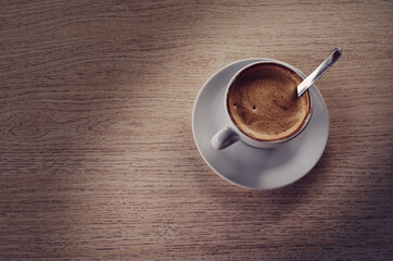 Taza de café con leche sobre mesa de madera.