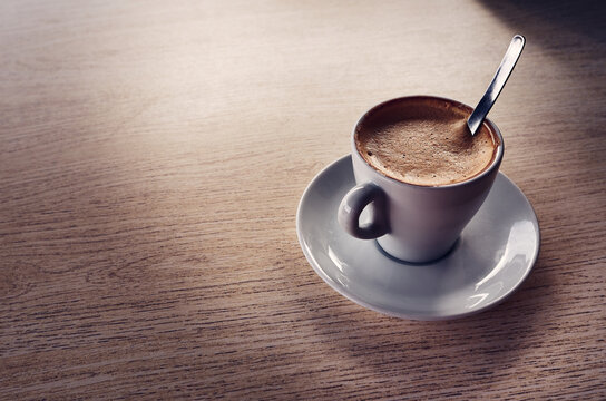 Cremosa taza de caf&eacute; con leche sobre mesa de madera antigua.