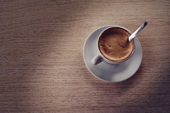 Taza de caf&eacute; con leche sobre mesa de madera.
