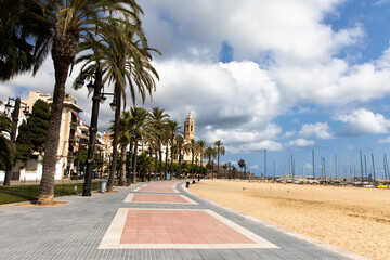 Empty promenade Passeig de la Ribera with the views of church Sant Bartomeu y Santa Tecla, Sitges, Catalonia, Spain © olly_plu