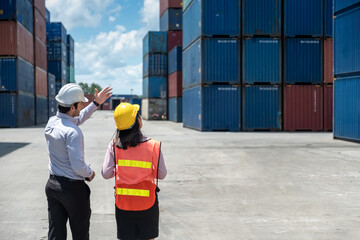 Shipping worker or engineer explain about work to Shipping woman worker colleague in shipyard factory with containers and sky background.