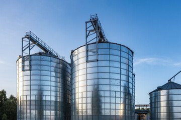 Modern Granary elevator with silver silos on agro-processing and manufacturing plant for processing drying cleaning and storage of agricultural products, flour, cereals and grain.