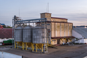 Modern Granary elevator with silver silos on agro-processing and manufacturing plant for processing drying cleaning and storage of agricultural products, flour, cereals and grain. © hiv360