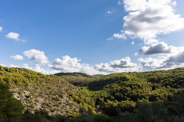 Fototapeta na wymiar Park natural Garraf, green mountains with blue sky and clouds, Mas alba, Sitges, Spain
