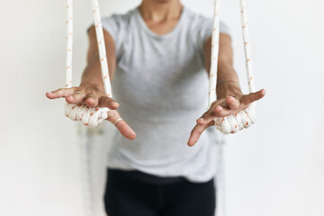 Closeup hands holding the rope, iyengar yoga at studio, white wall
