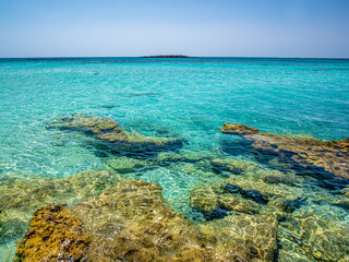 Fototapeta na wymiar Elafonisi Crete Beach view to crystal clear water with nature rocks at the background