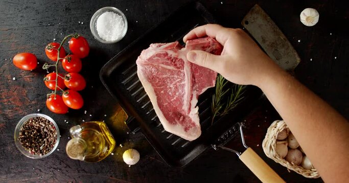 The men's hand puts the raw t-bone steak beef in the pan.