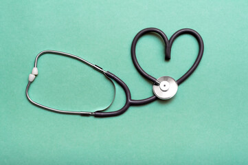 Stethoscope in Shape of Heart Isolated On Green Background.