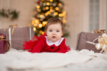 Portrait of happy little girl in red knitted sweater with Christmas present box near Christmas tree. Happy childhood. Waiting for a Christmas tale