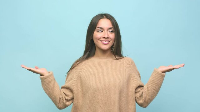 Young cute woman makes scale with arms, feels happy and confident