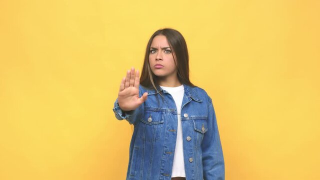 Young cute woman standing with outstretched hand showing stop sign, preventing you