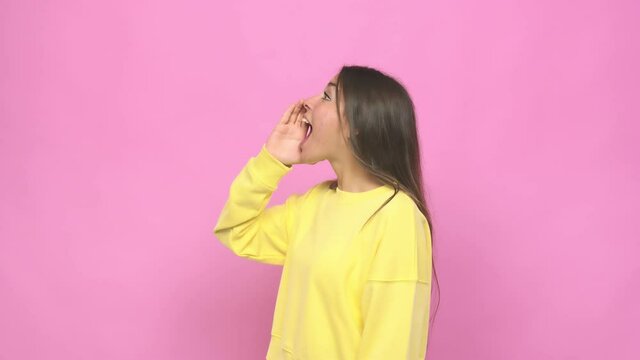 Young cute woman shouting and holding palm near opened mouth