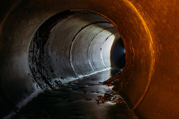 Flooded round sewer tunnel with water reflection