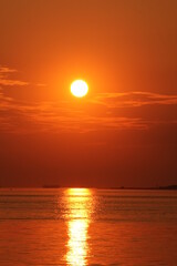 a beautiful sunset at the dutch coast at a warm summer evening with an orange sky and water of the westerschelde sea with a sunbeam