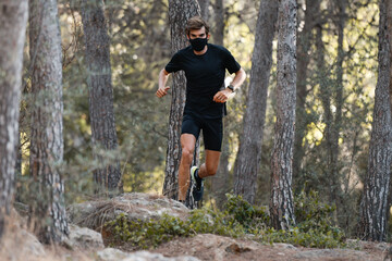 Obraz premium Atleta corriendo por el bosque con una mascarilla de tela negra