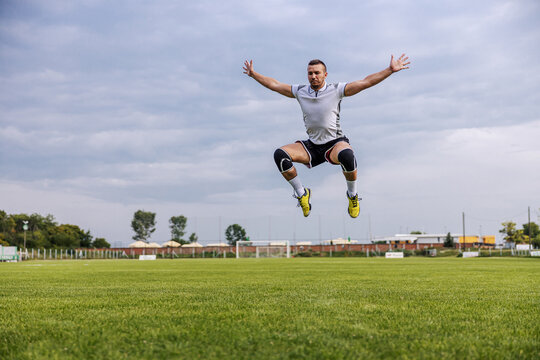 Attractive soccer player in shape doing jumping exercises on the field.