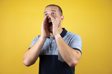 Russian man standing over insolated yellow background shouting and screaming loud to side with hand on mouth. Communication concept.